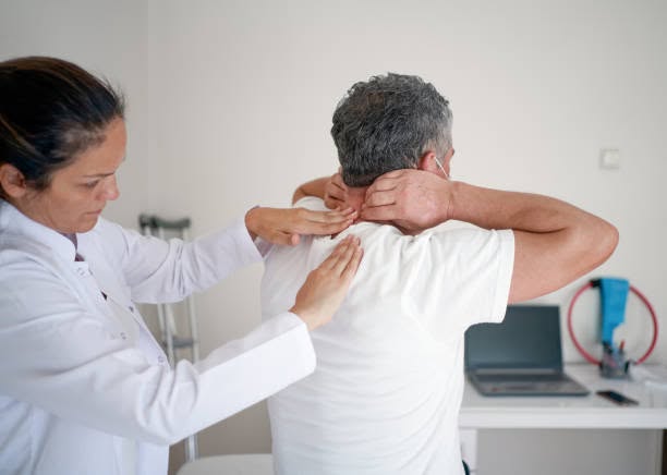 Doctor examining a patient's neck and upper back in a medical office
