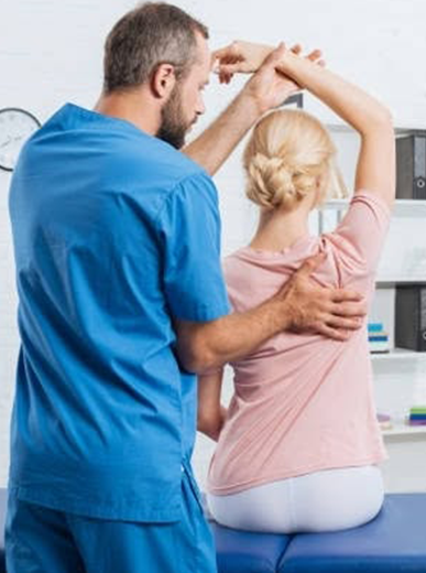 Physical therapist guiding a patient through a back and shoulder stretching exercise during a clinical session