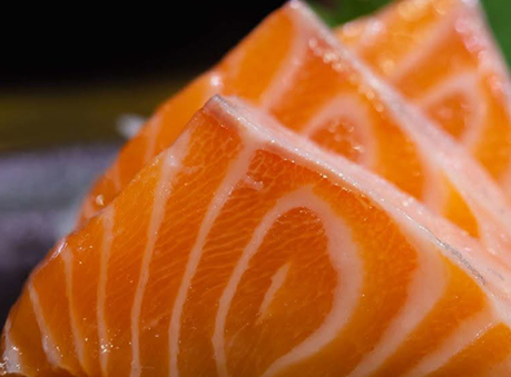 Close-up of fresh salmon sashimi slices showing vibrant orange flesh with white fat marbling